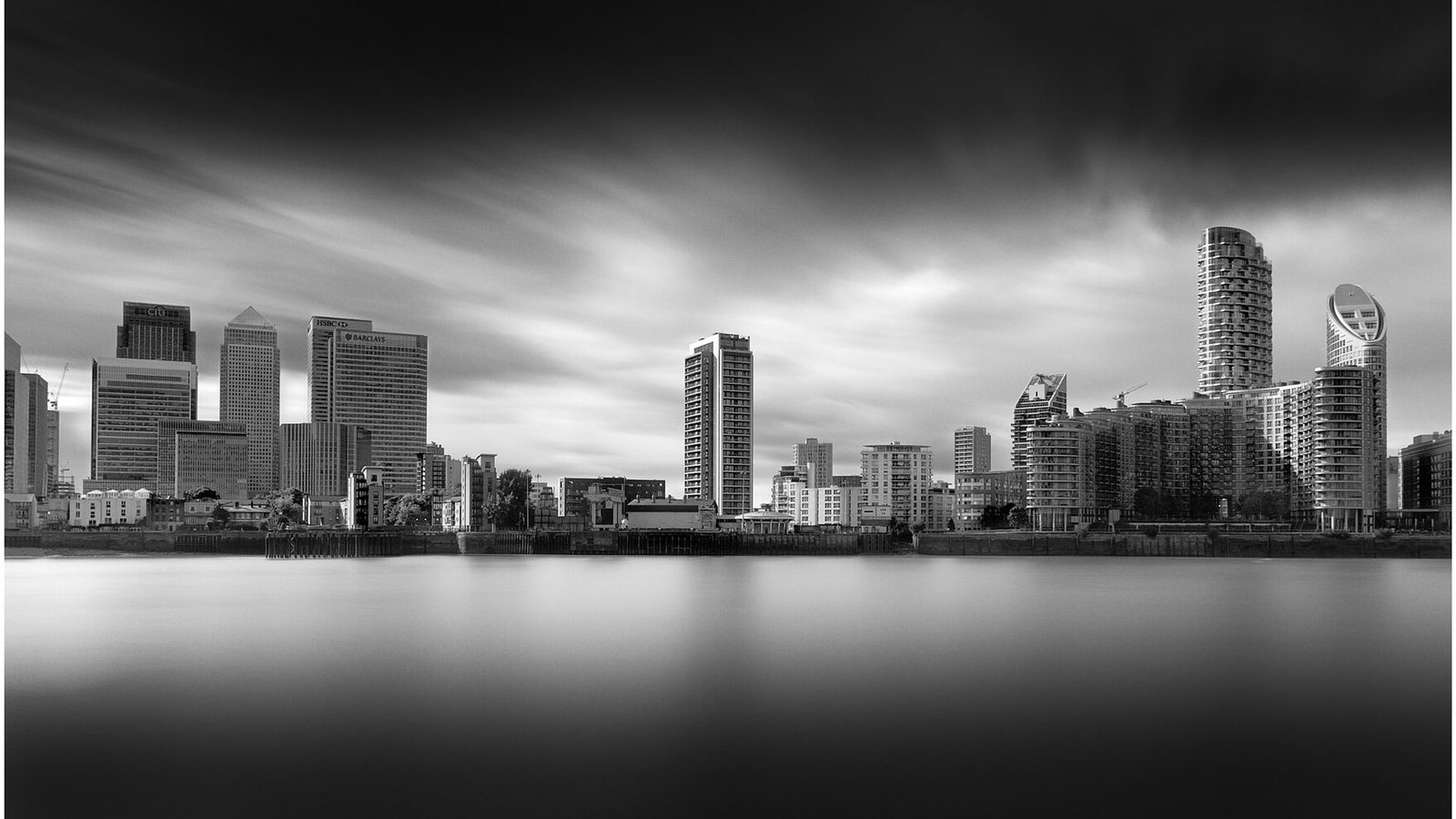 The towers of London's Canary Wharf financial district, each carrying a different bank's name, seen across the Thames