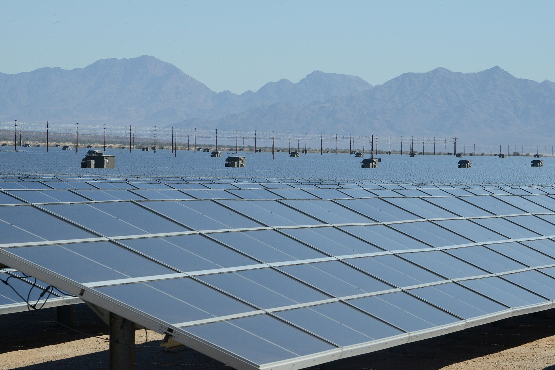 A large field of photovoltaic solar panels at a desert solar farm